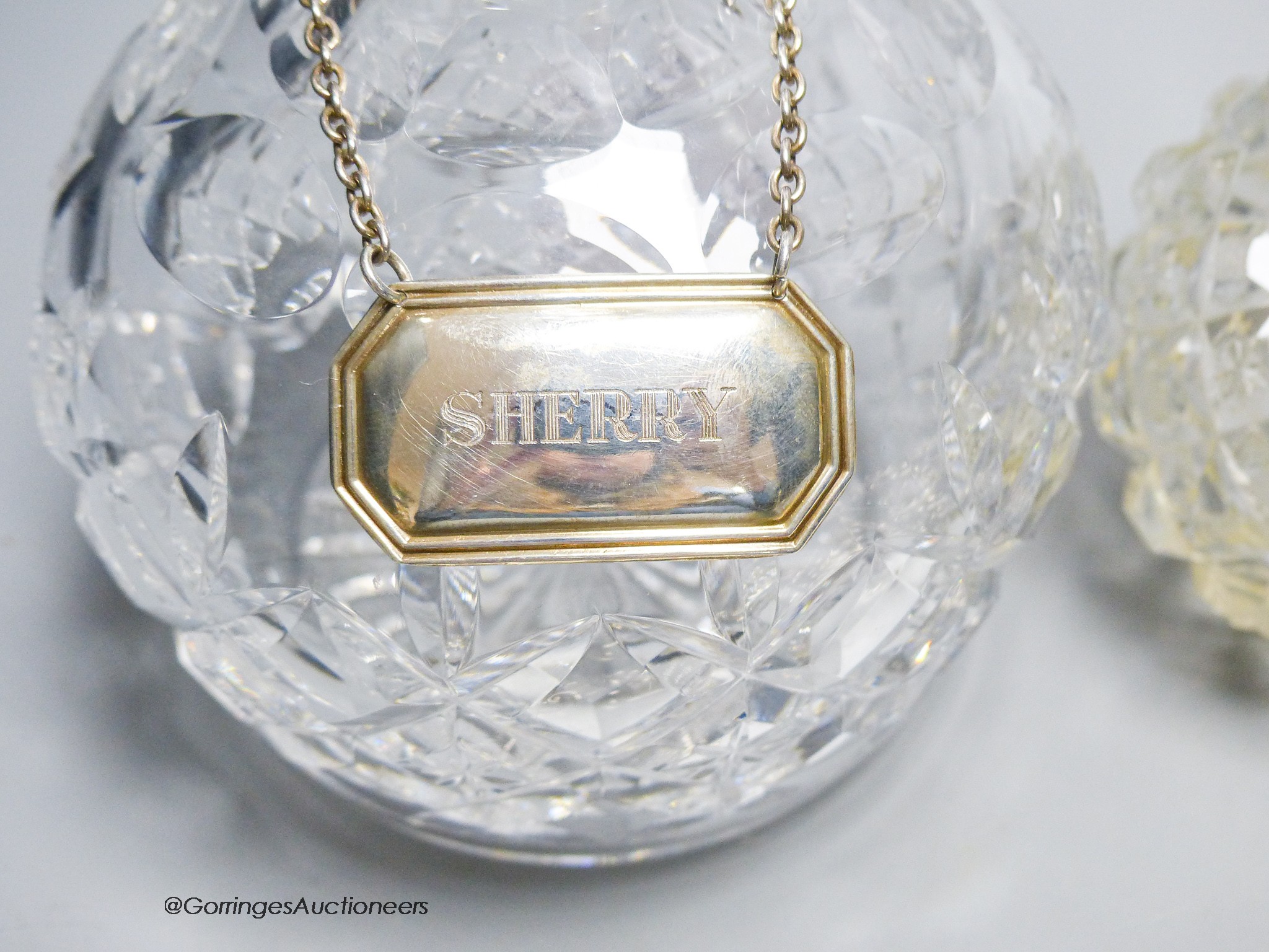 A pair of George V silver mounted scent bottles, (a.f.) 11.6cm, a repousse silver mounted hand mirror and a glass decanter with a silver wine label.
